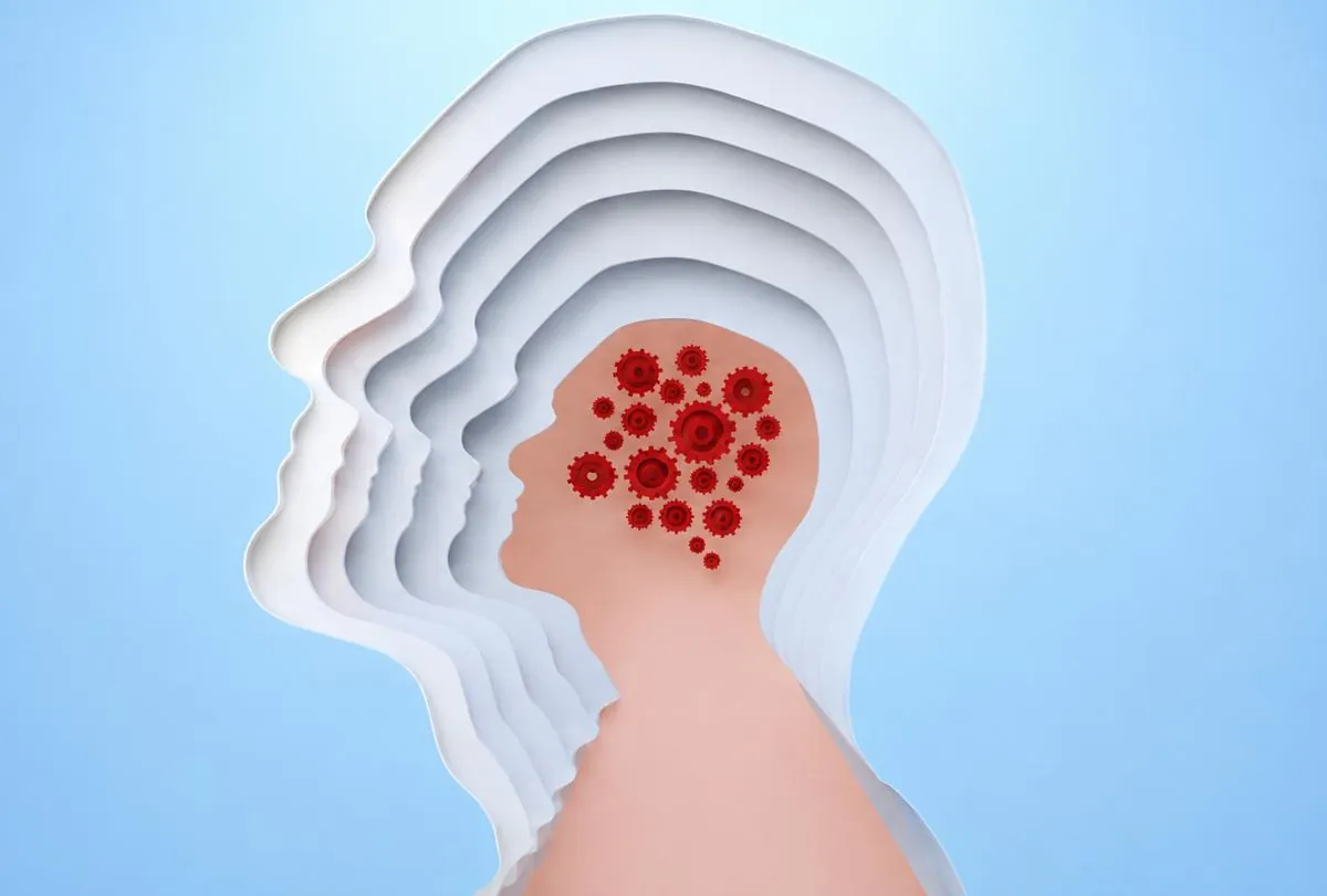Layered paper-cut head profile with a cluster of red spots in the brain area