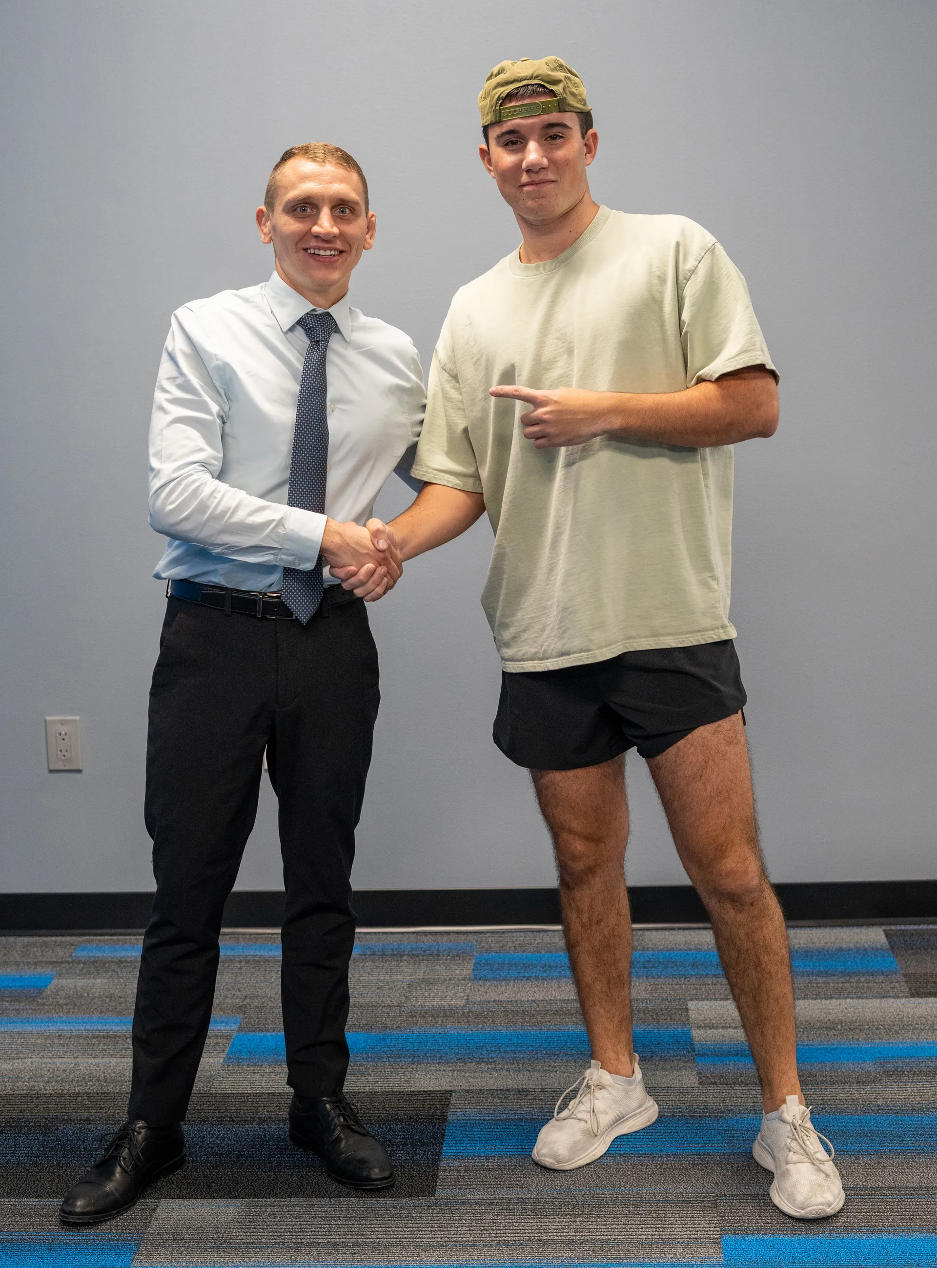 Dr. Jacoby Bergeron shaking hands with a patient in a green T-shirt and shorts