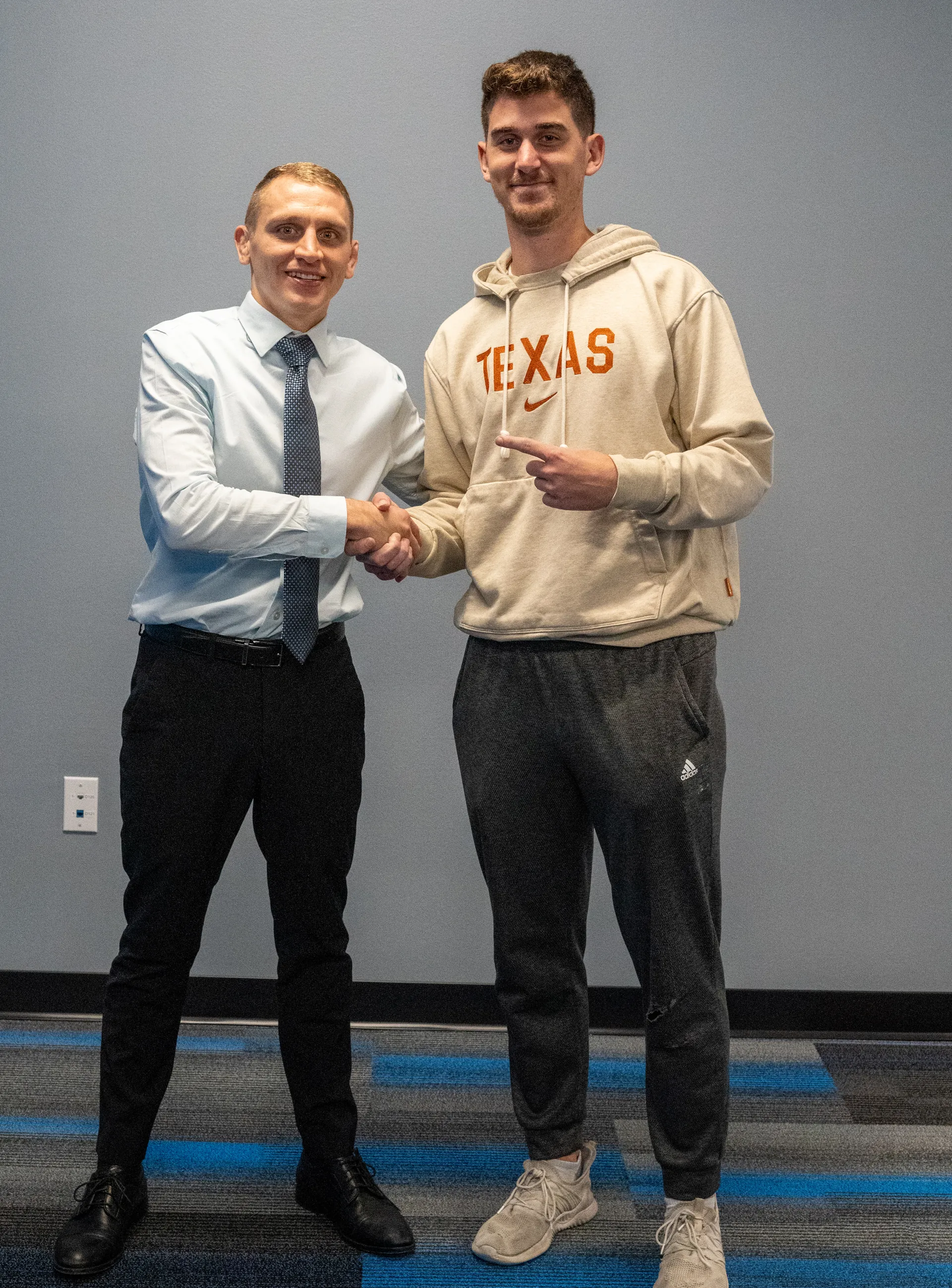 Dr. Jacoby Bergeron shaking hands with a patient in an orange Texas hoodie
