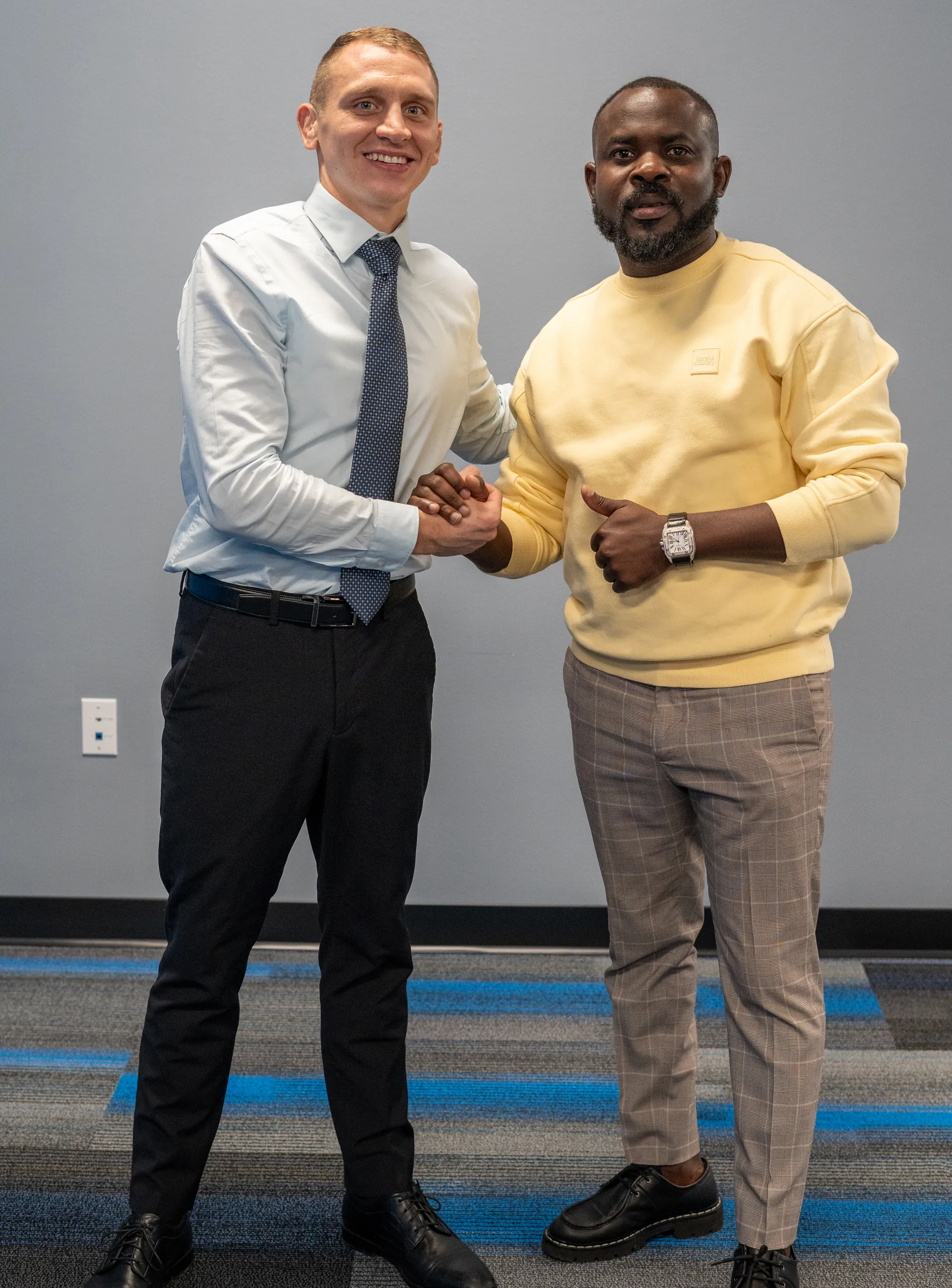 Dr. Jacoby Bergeron shaking hands with a patient in a yellow sweater