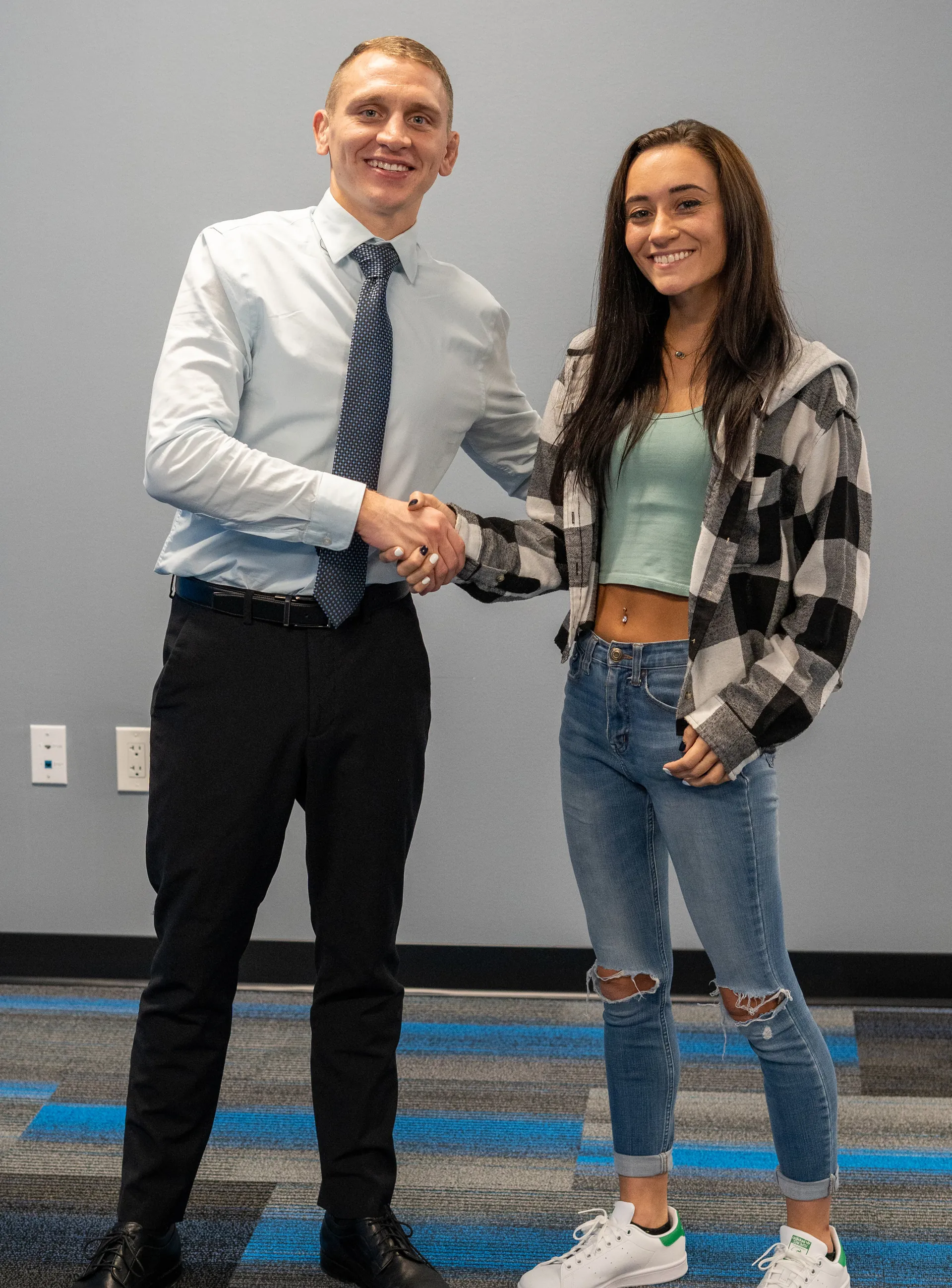 Dr. Jacoby Bergeron shaking hands with a smiling patient in a plaid shirt