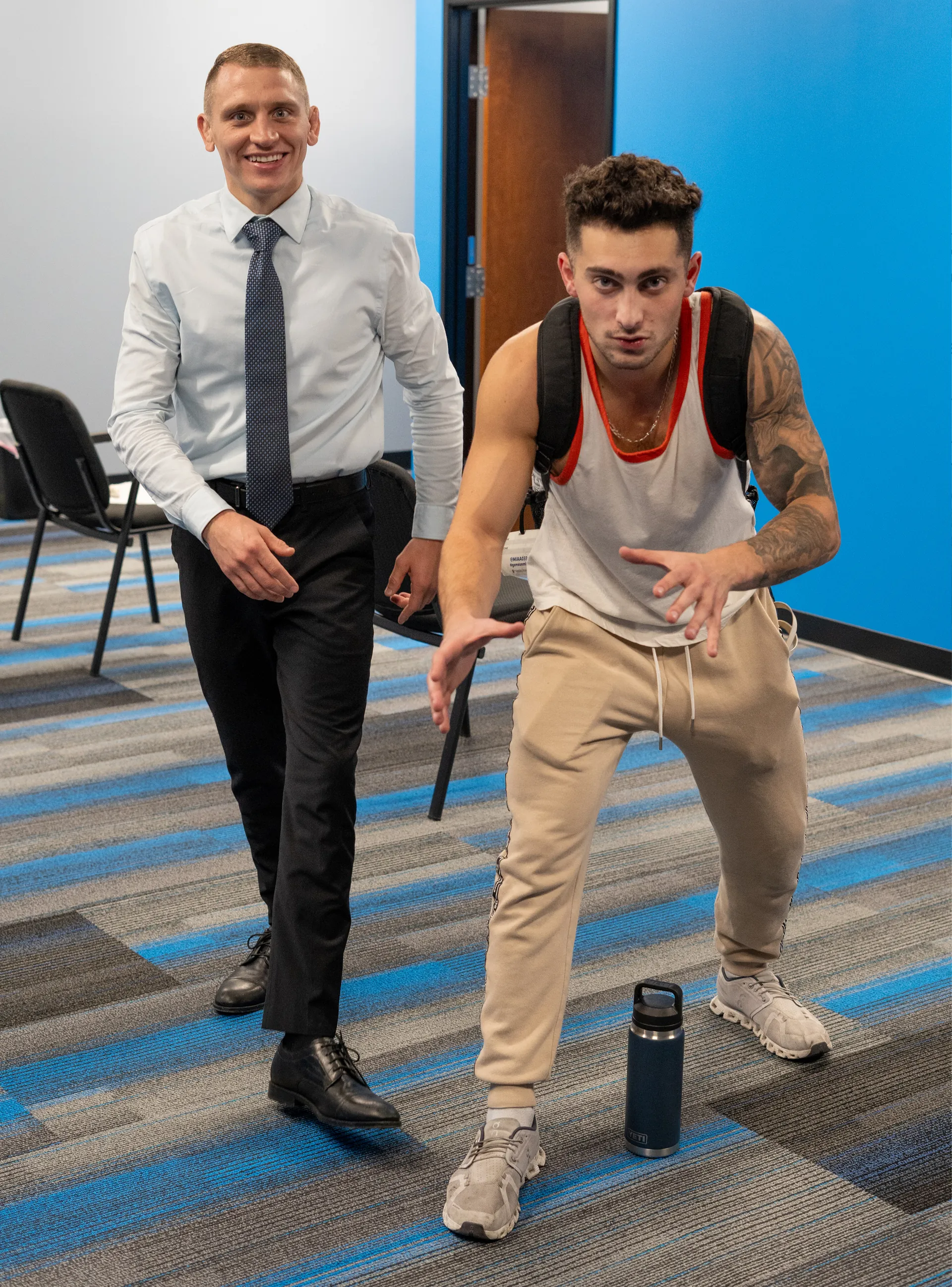 Patient in a tank top and backpack striking a playful pose beside Dr. Jacoby Bergeron