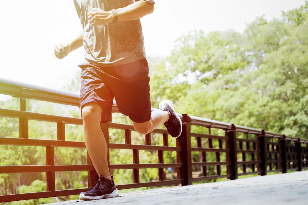 Runner jogging along a tree-lined footbridge